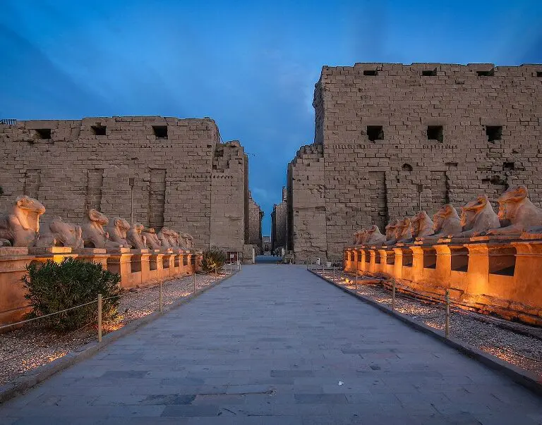 This image might depict the Karnak Temple Complex located in Luxor, Egypt. The complex is a vast collection of temples, pylons, and other structures, and is one of the largest religious sites in the world. The statue in the foreground may be a sphinx, a mythical creature with the body of a lion and the head of a human or animal.