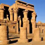 A photo of the Temple of Kom Ombo at night, an ancient Egyptian temple with tall columns illuminated against a starry sky.